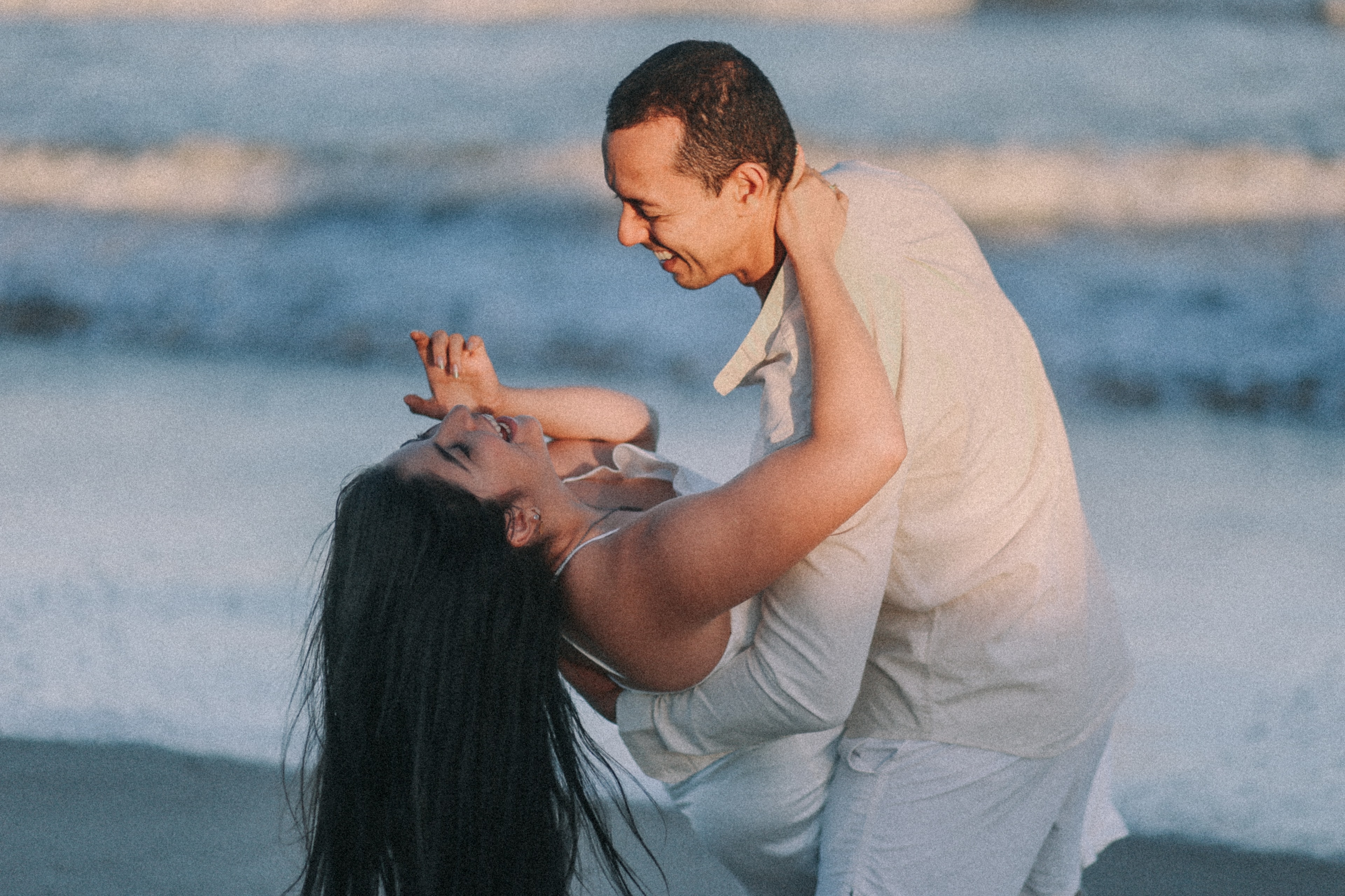 Casal dançando na praia ao pôr do sol